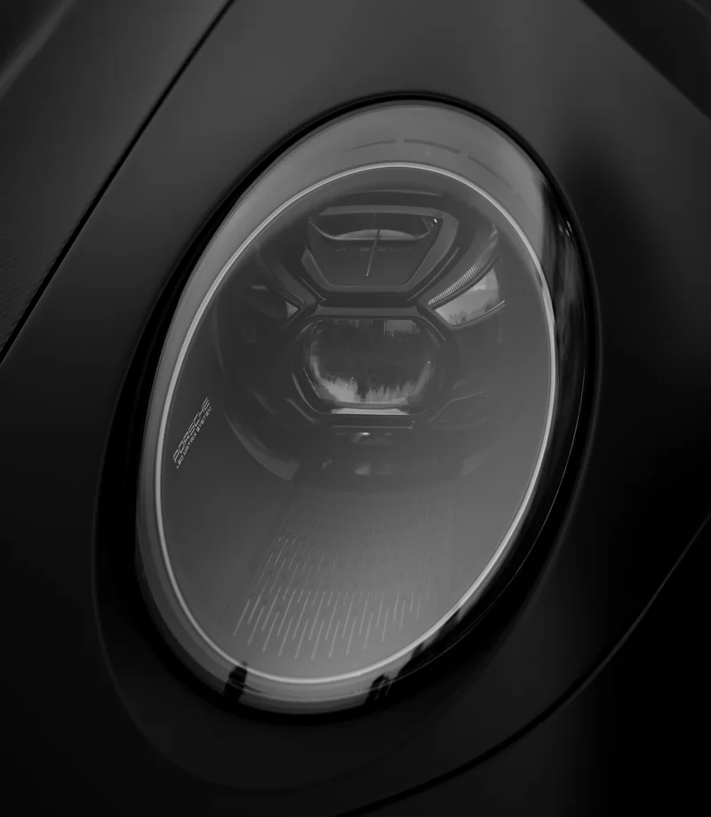 An understated close-up of a sports car headlight and sculpted bodywork